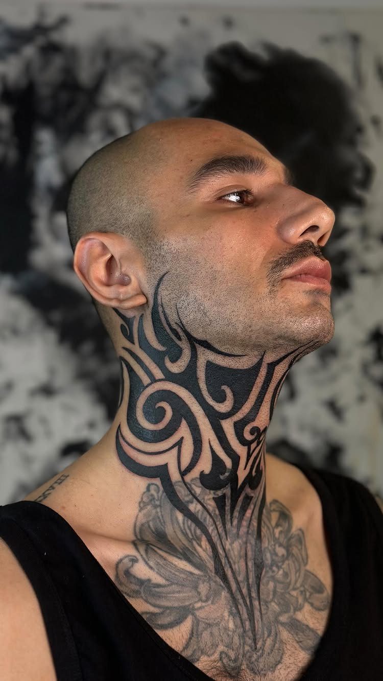 Man with bold black curved tribal tattoos on his neck and chest.