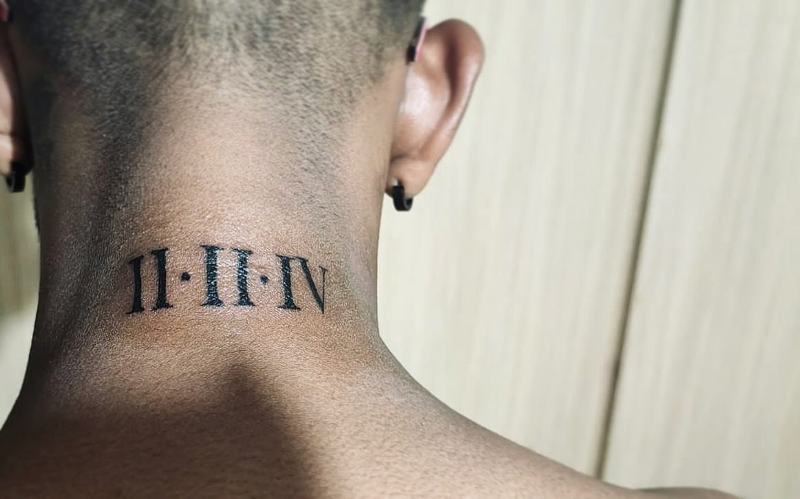 Roman numeral tattoo on the back of a person's neck in black ink.