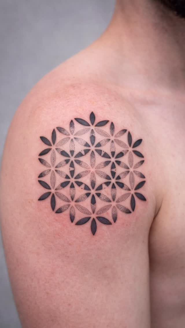 Flower of Life geometric tattoo in black ink on a person's shoulder.
