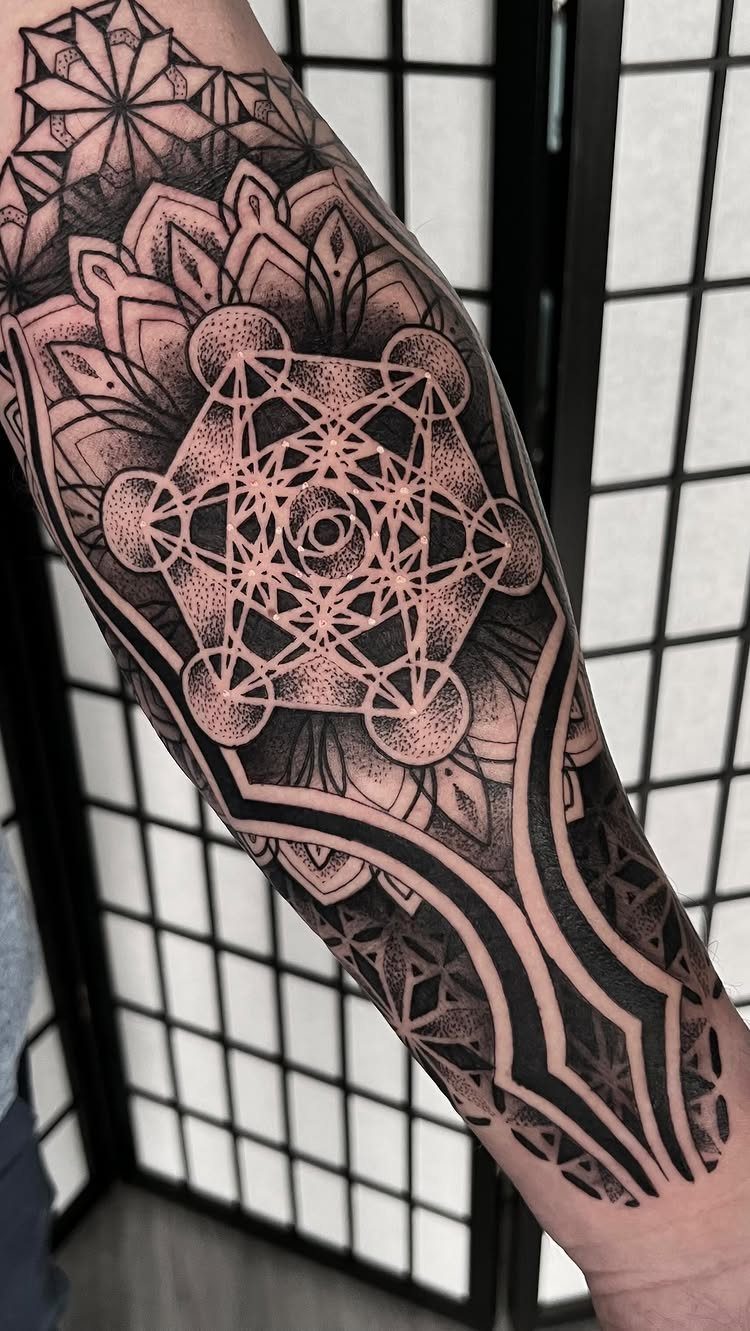Metatron's Cube tattoo on an arm with intricate black ink geometric patterns.