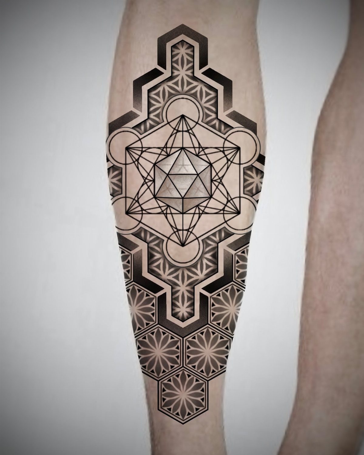 Sacred geometry tattoo on a forearm featuring a central cube and hexagonal patterns.