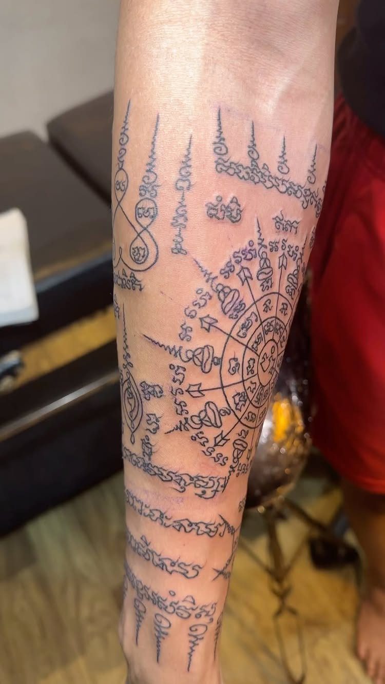 Sak Yant tattoo on a forearm with traditional Thai script and mandala patterns