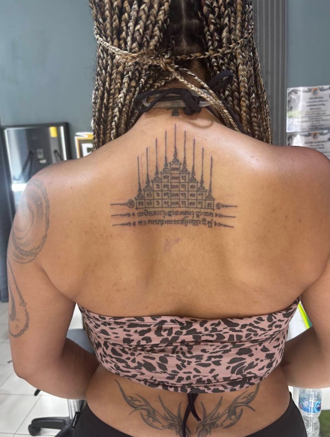 Sak yant tattoo of a temple and script on a person's upper back