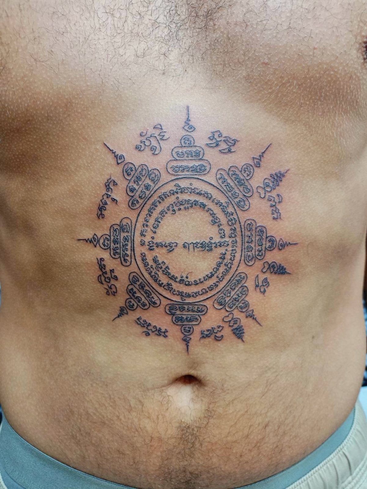 Paed Tidt Sak Yant tattoo with eight directions on a person's abdomen