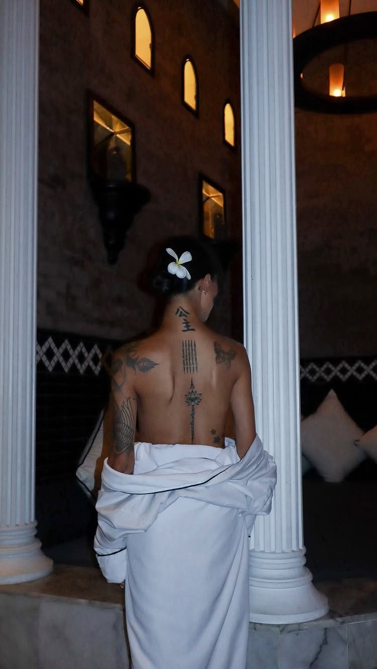 Woman with Sak Yant tattoos on her back and arm wearing a white wrap