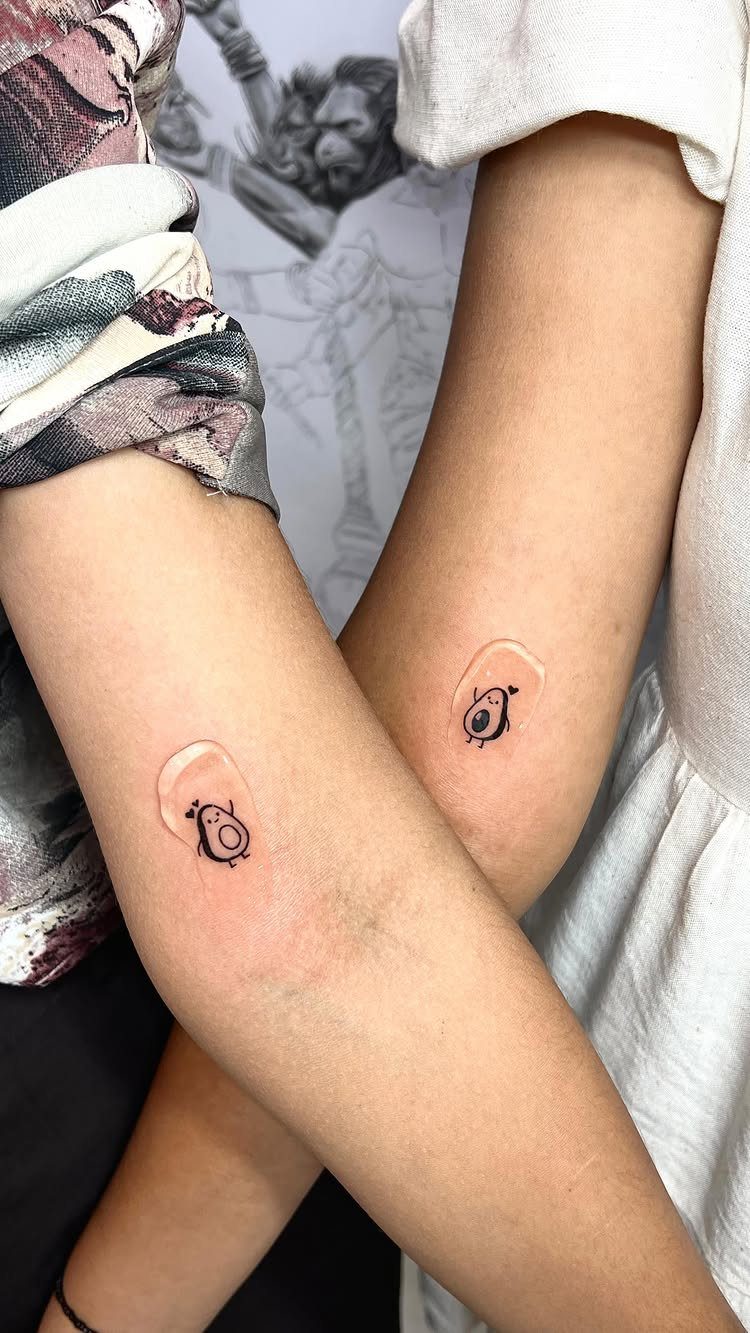 Two small avocado tattoos on the inner forearms of a couple.
