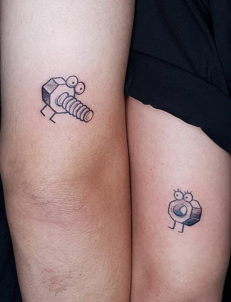 Matching cartoon bolt and nut tattoos on two people's legs.