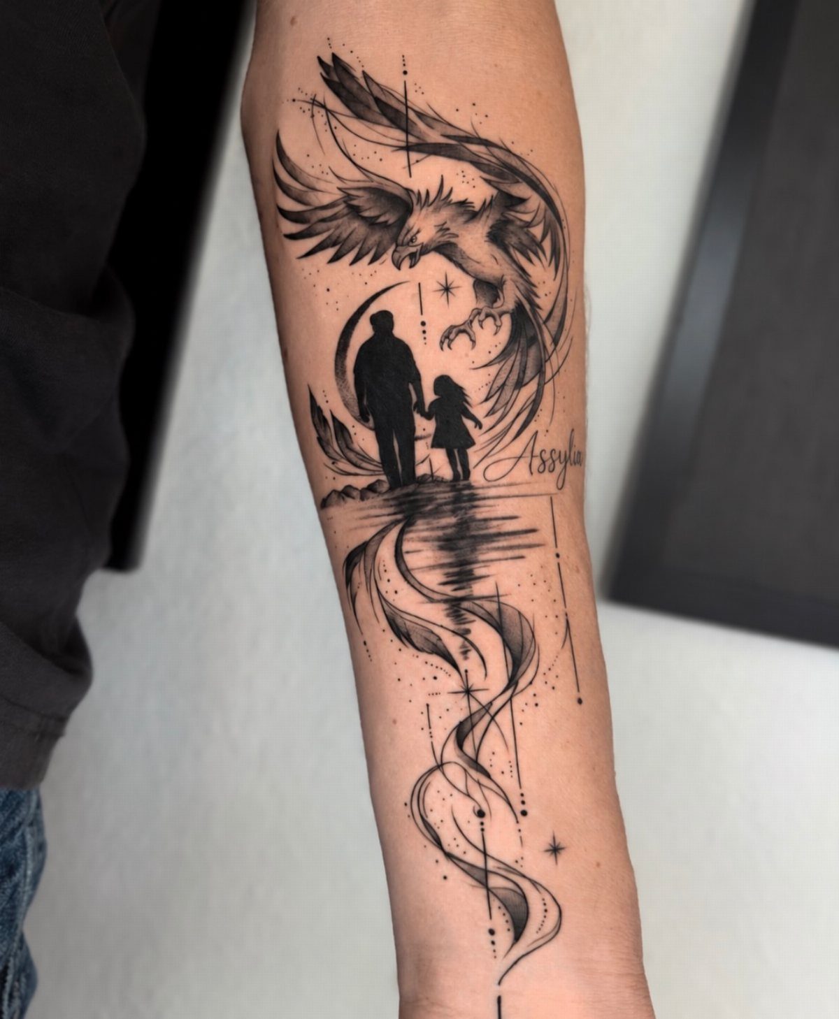 Eagle tattoo on forearm above silhouettes of a father and daughter holding hands.