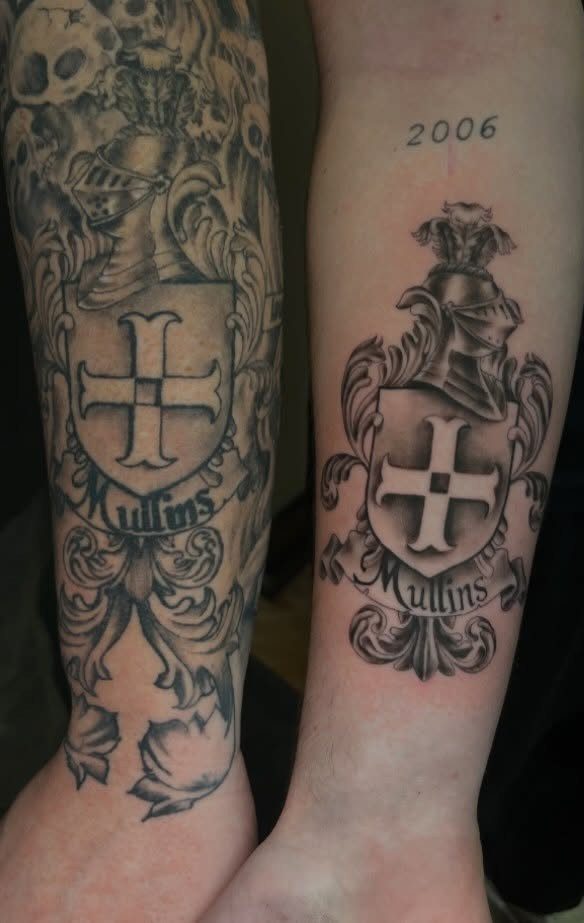 Matching family crest tattoos on two arms featuring a shield and the name Mullins