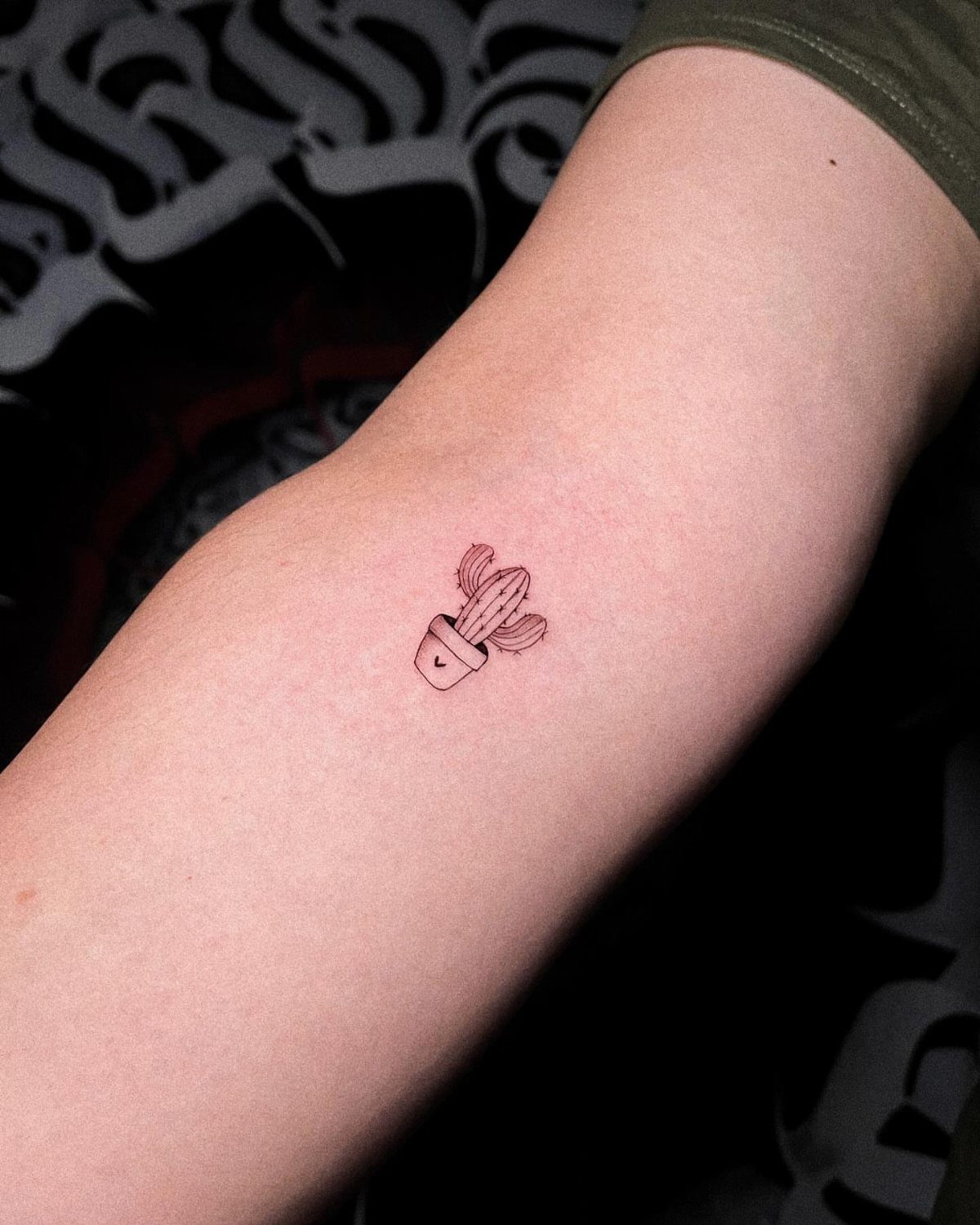 Small minimalist cactus in a pot tattoo on a person's forearm