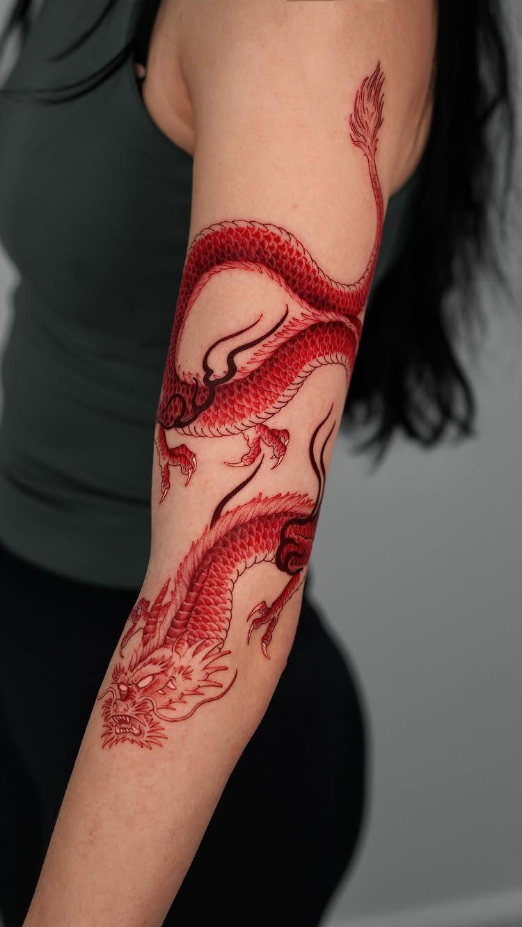 Red dragon tattoo winding down a person's forearm with detailed scales and claws.