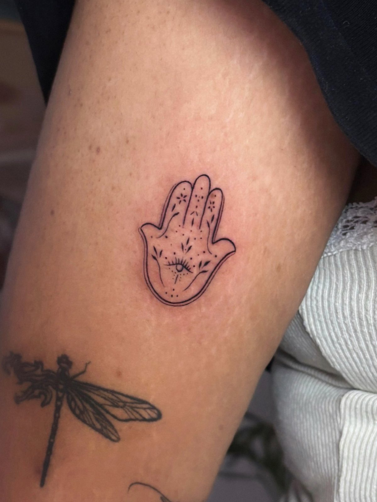 Hamsa hand tattoo with an eye centered on a person's skin.