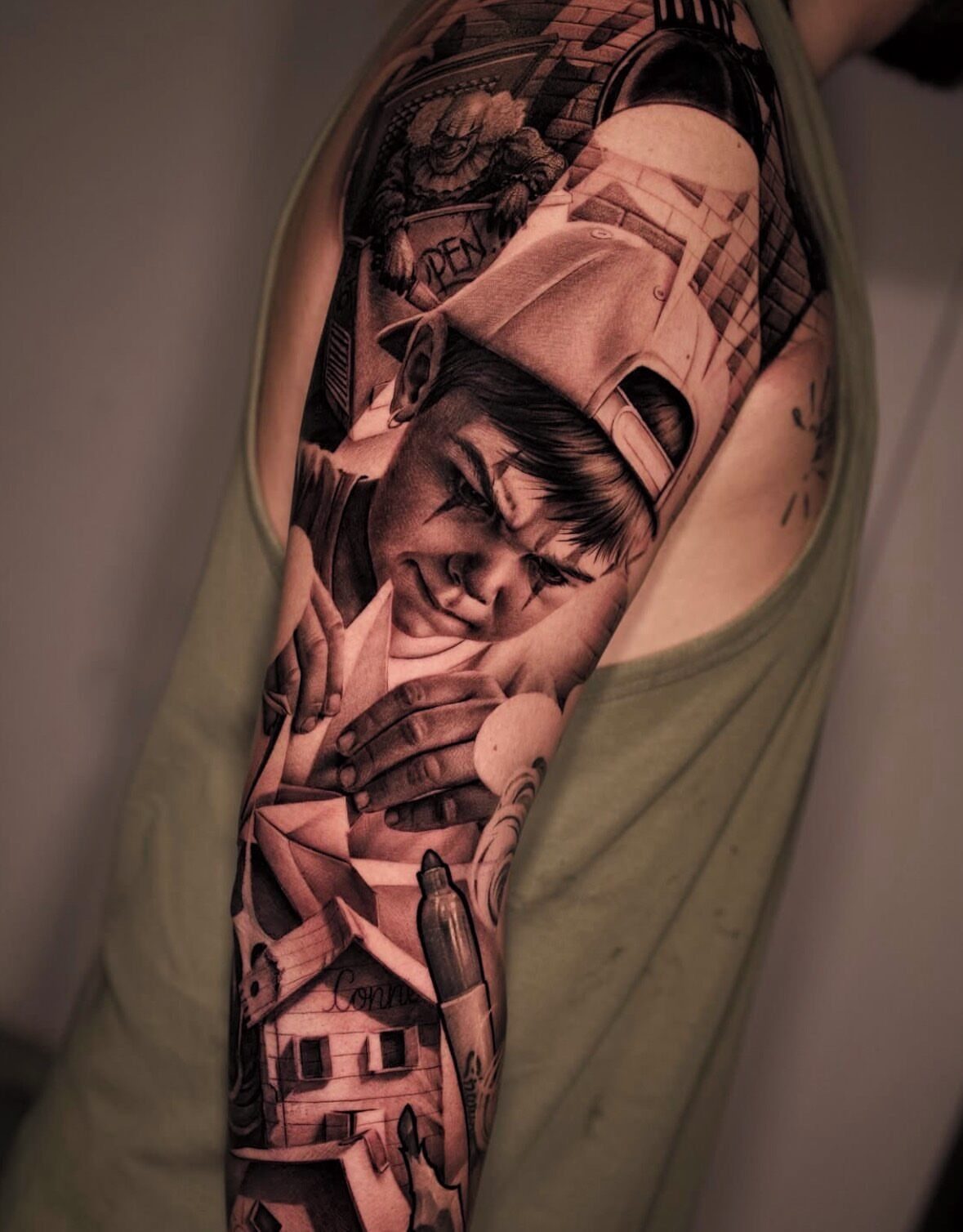 Detailed black-and-gray arm tattoo featuring a young boy and narrative scenes.