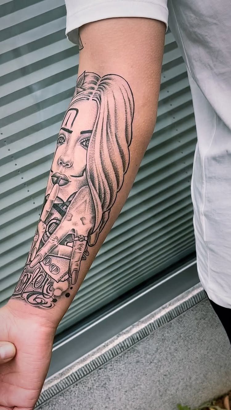 Black and gray Chicano style tattoo of a woman's portrait on a forearm.