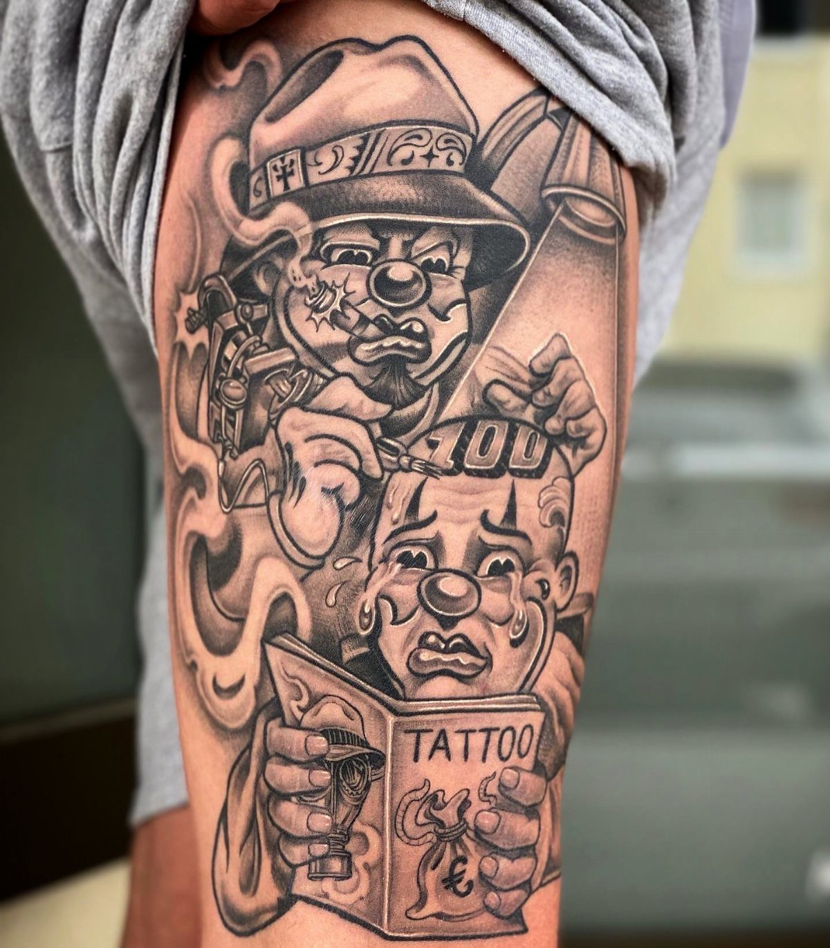 Black and gray tattoo of two clowns on a person's leg.