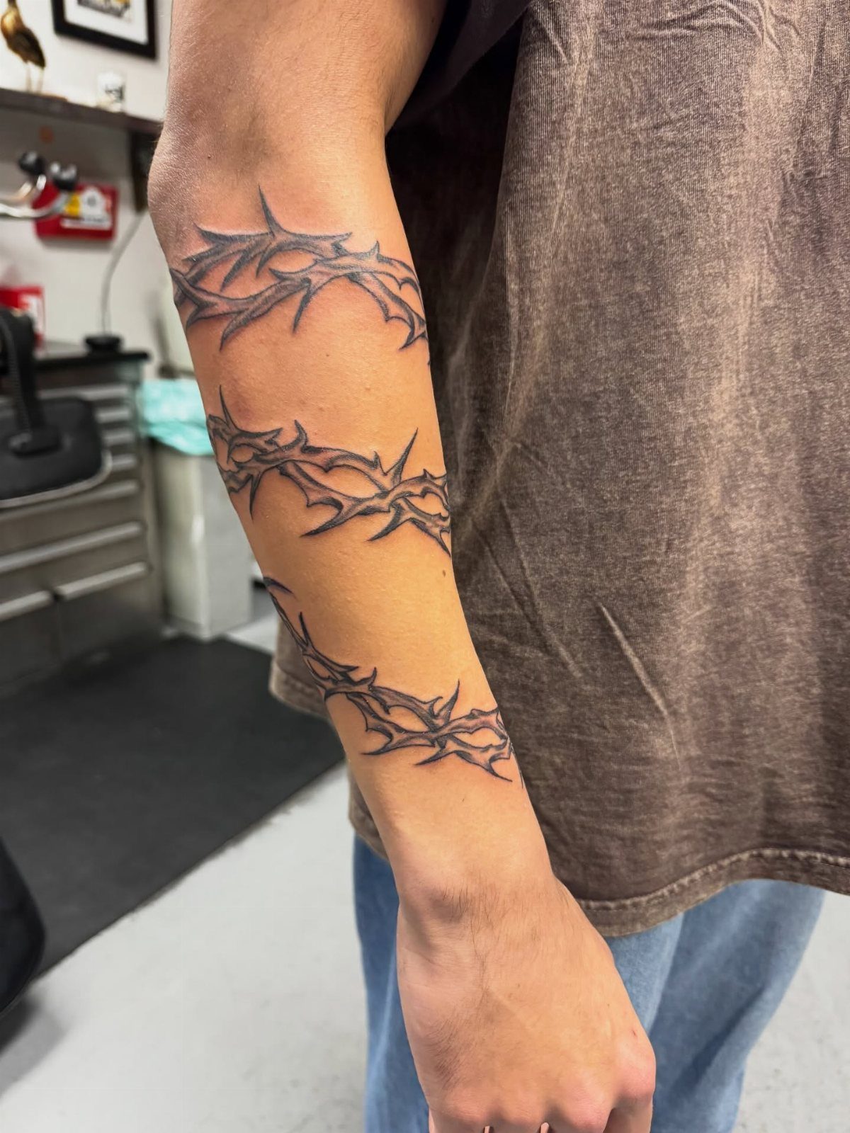 Forearm with three black ink tattoo bands of thorny vines wrapping around.