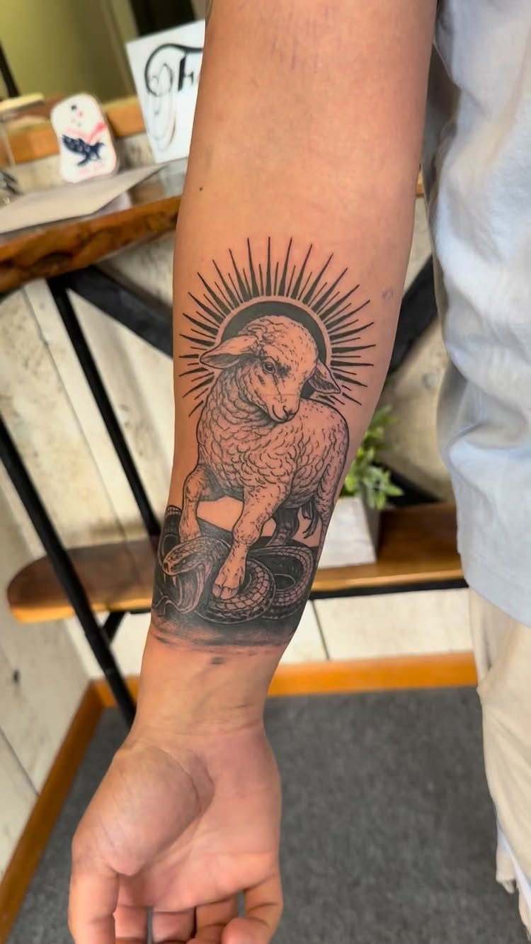 Lamb of God tattoo on a forearm featuring a halo and a snake.