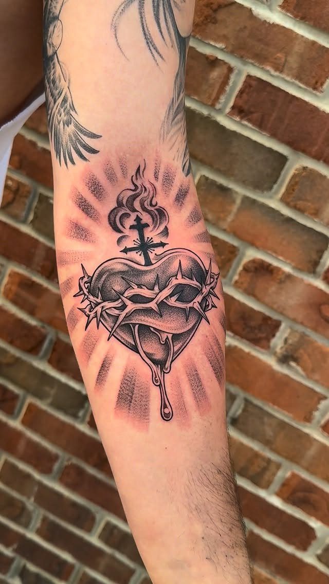 Sacred Heart tattoo with crown of thorns and cross on a forearm