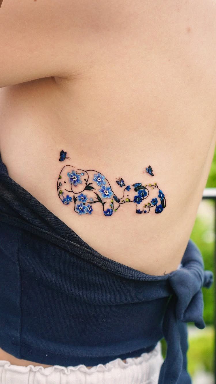 Elephant tattoo with blue floral patterns and butterflies on a person's side