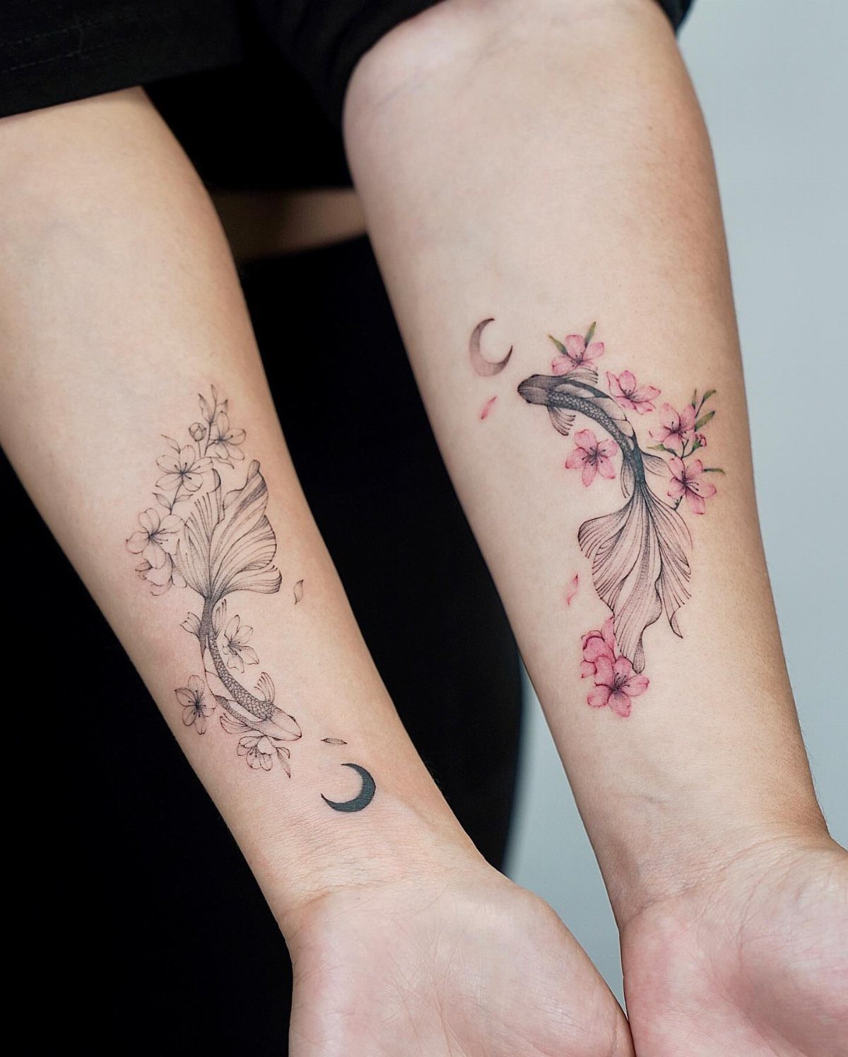 Matching koi fish tattoos with cherry blossoms and moons on two forearms.