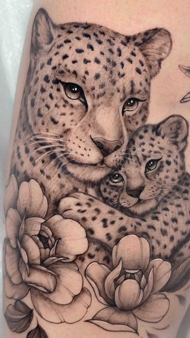Leopard and cub cuddling tattoo with large flowers in black and grey ink.