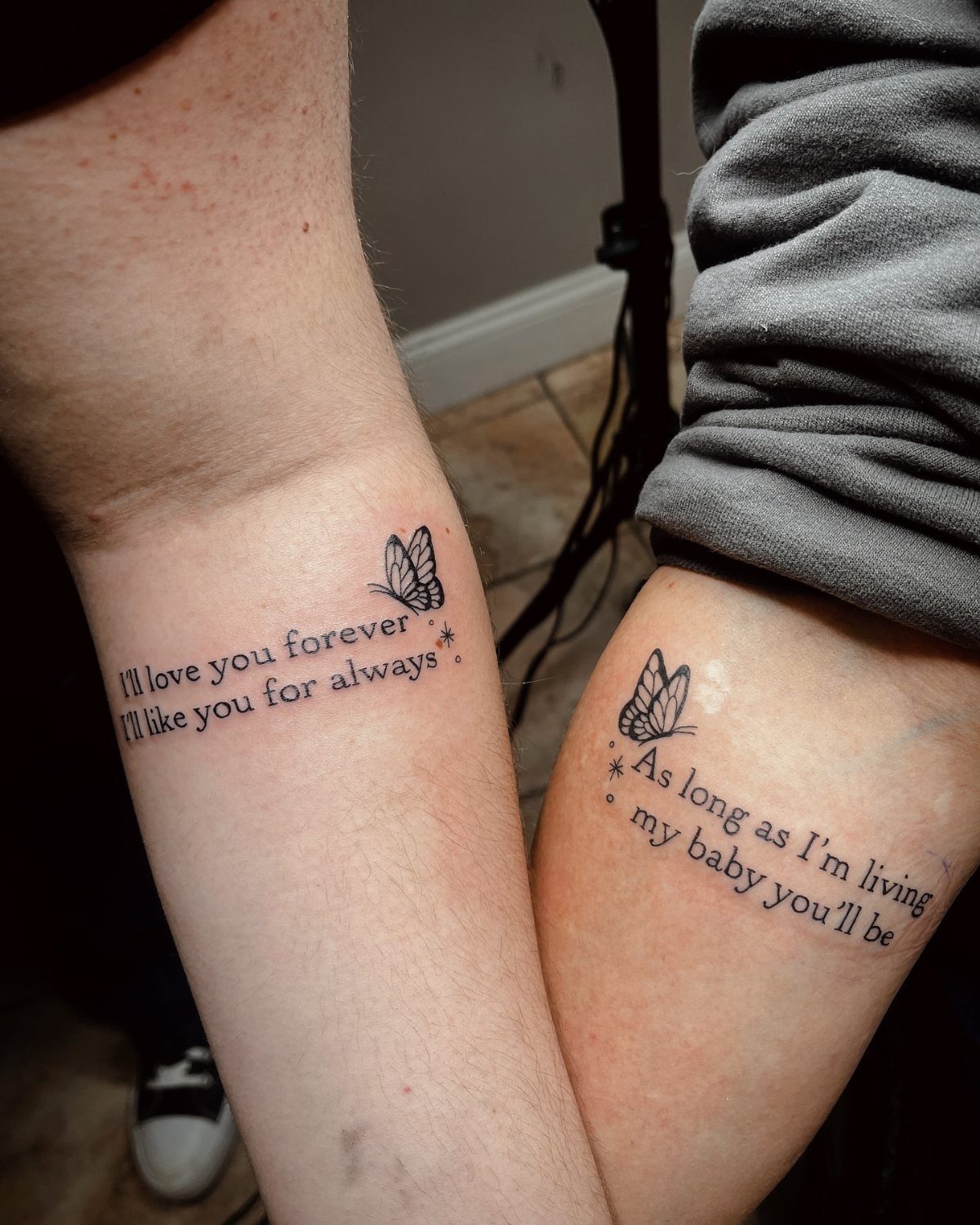 Two arms with matching butterfly and quote tattoos about a mother and child.