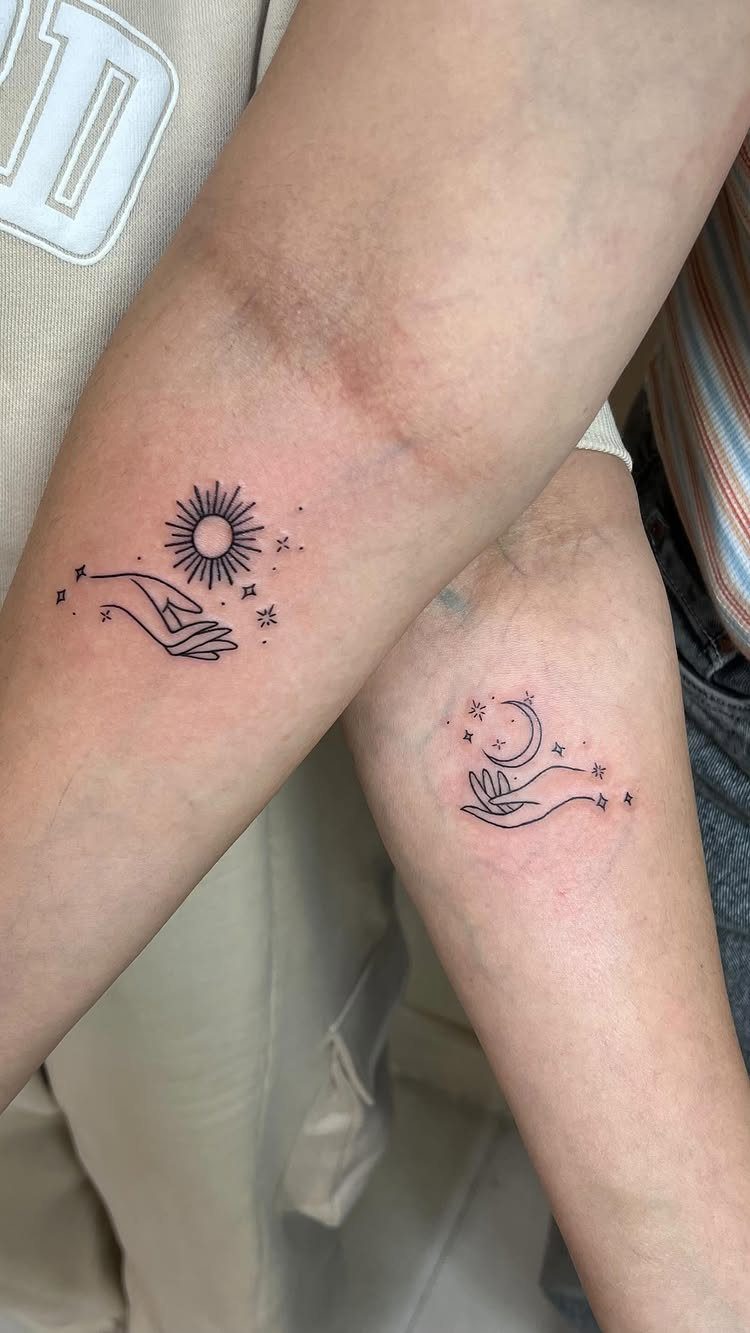 Two forearms with matching tattoos of a sun and a crescent moon.