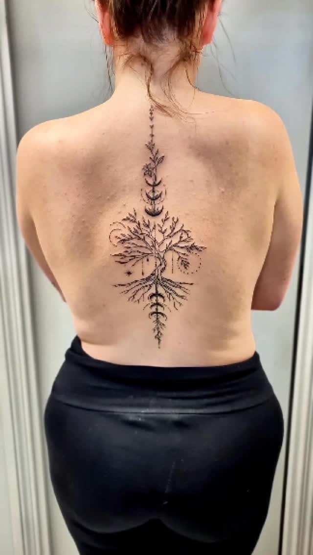 Stylized black ink family tree tattoo centered vertically on a person's back.