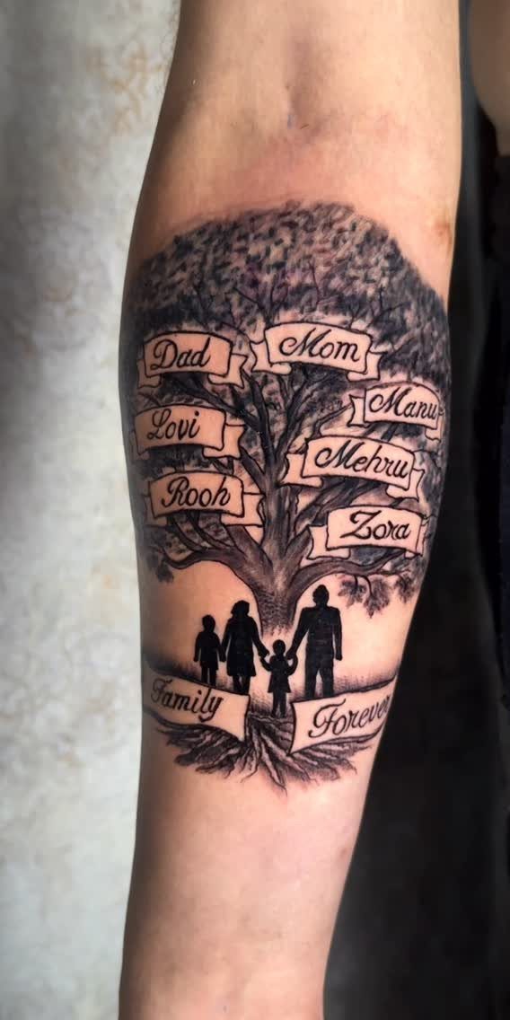 Family tree tattoo on forearm with names in banners and family silhouettes