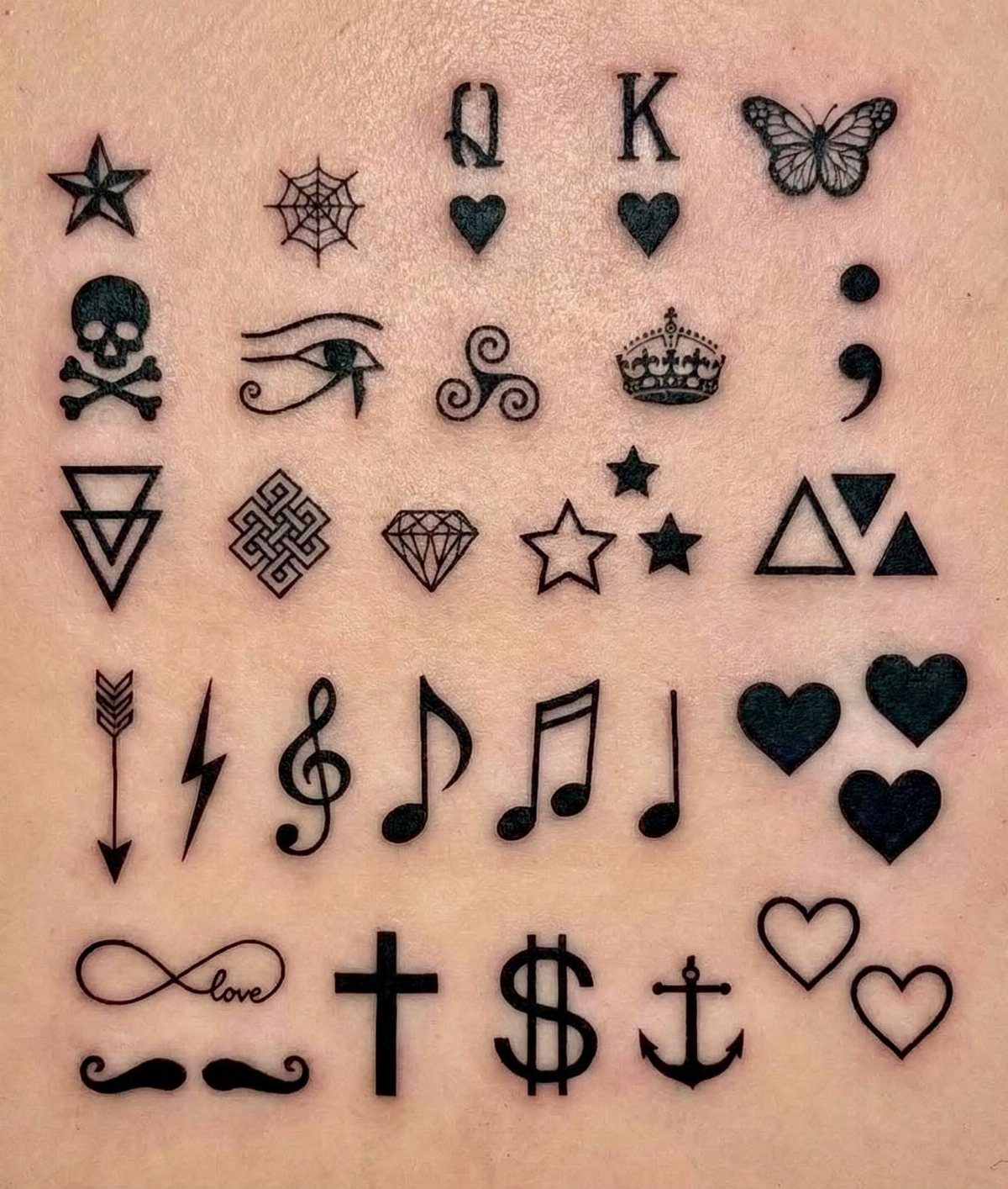 Small black ink tattoo symbols arranged in a grid on human skin.