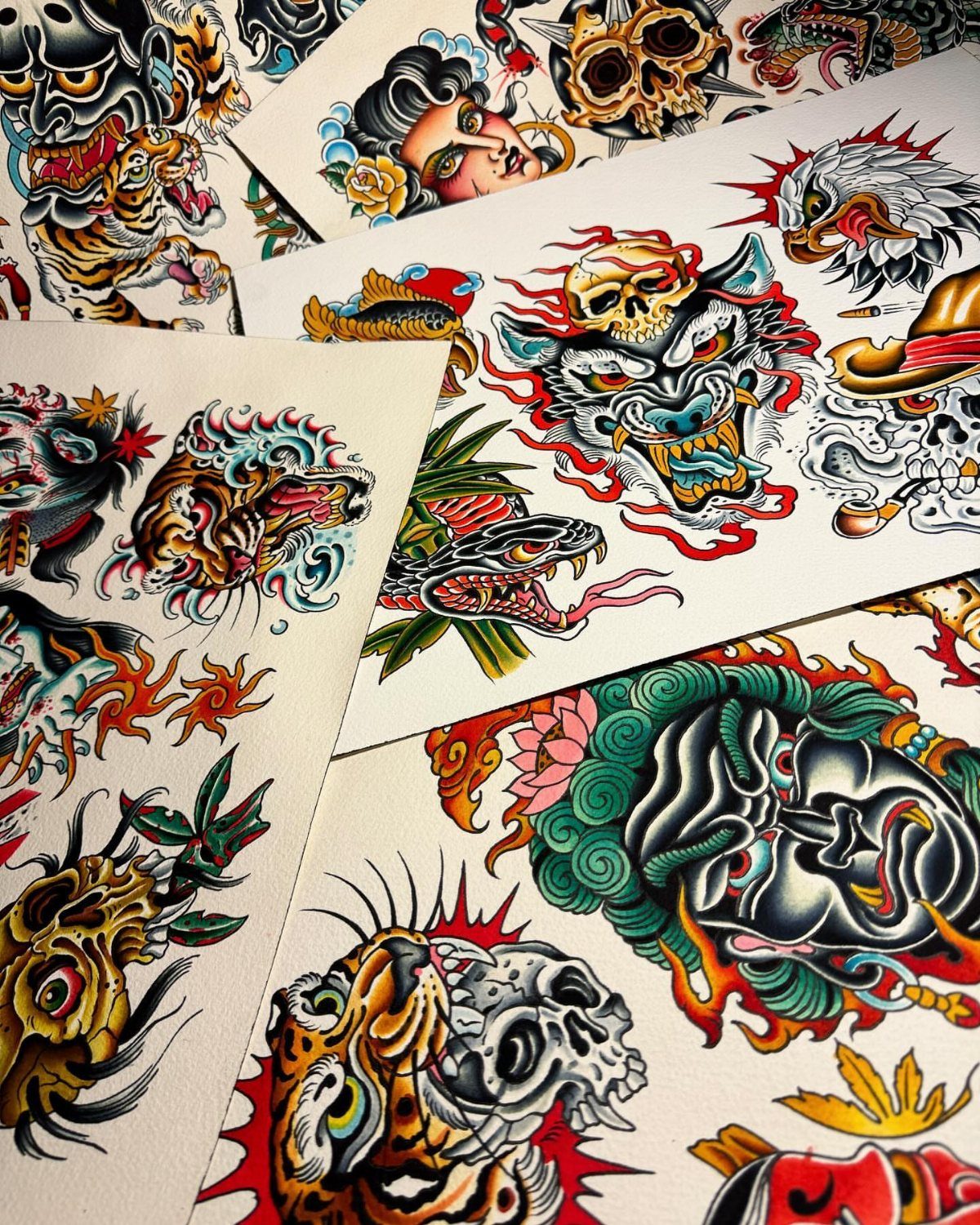 Tattoo flash sheets featuring traditional designs of tigers, skulls, and faces.