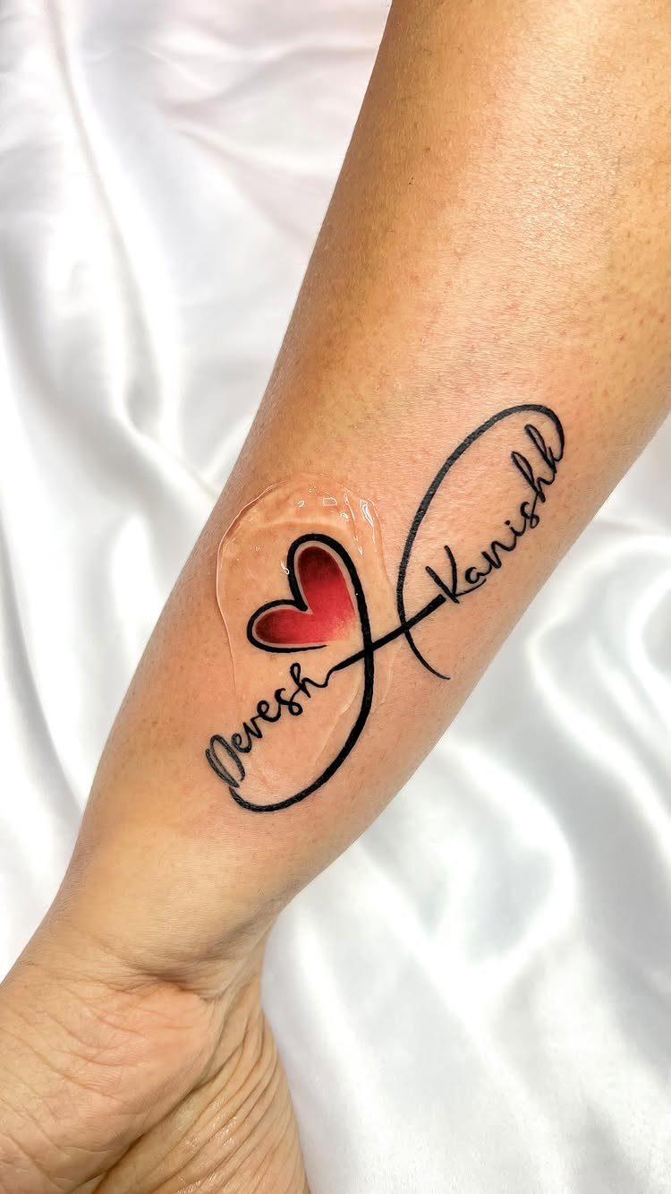 Infinity symbol tattoo on a forearm with names Devesh and Kanishk and a red heart