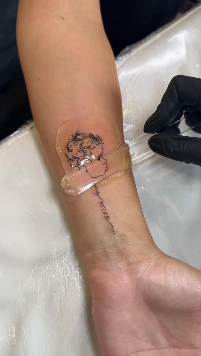 Child's profile portrait tattoo on a forearm with a handwritten name below.