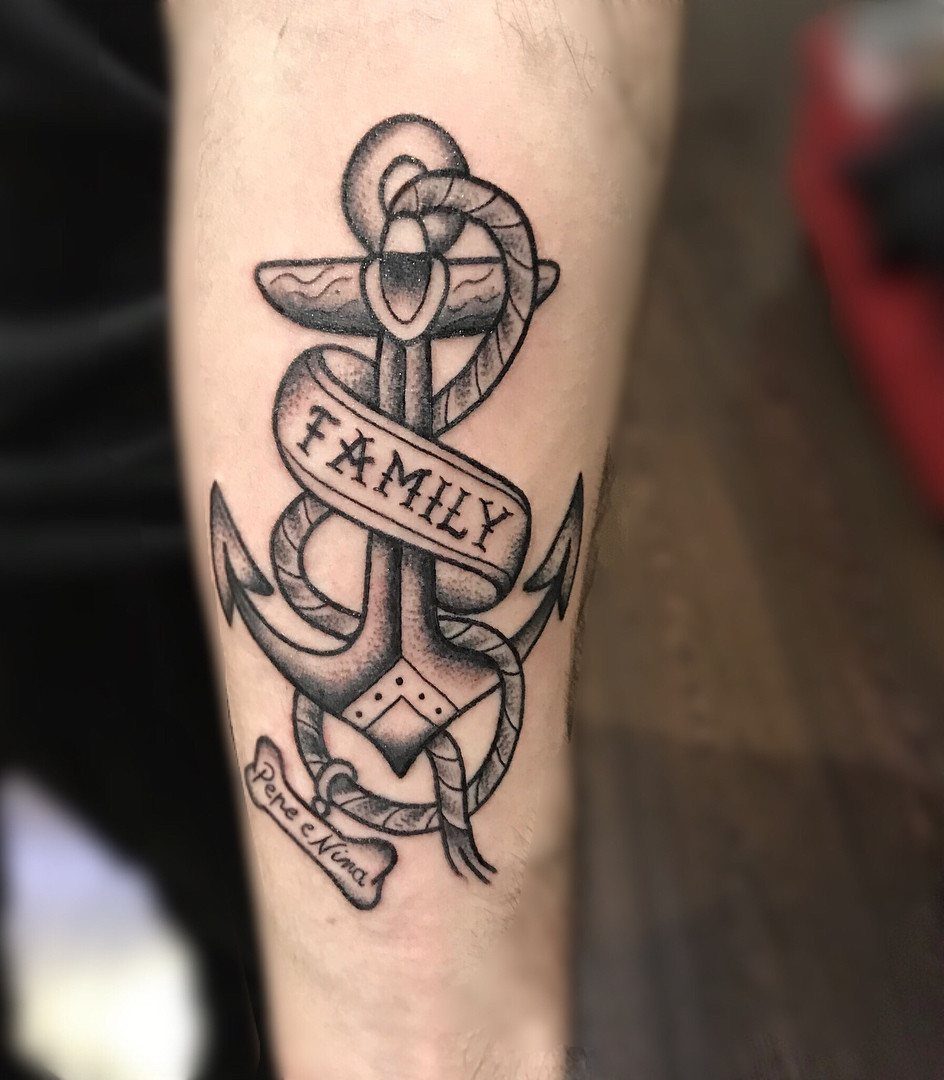 Anchor tattoo on a forearm with a banner reading FAMILY and a rope.