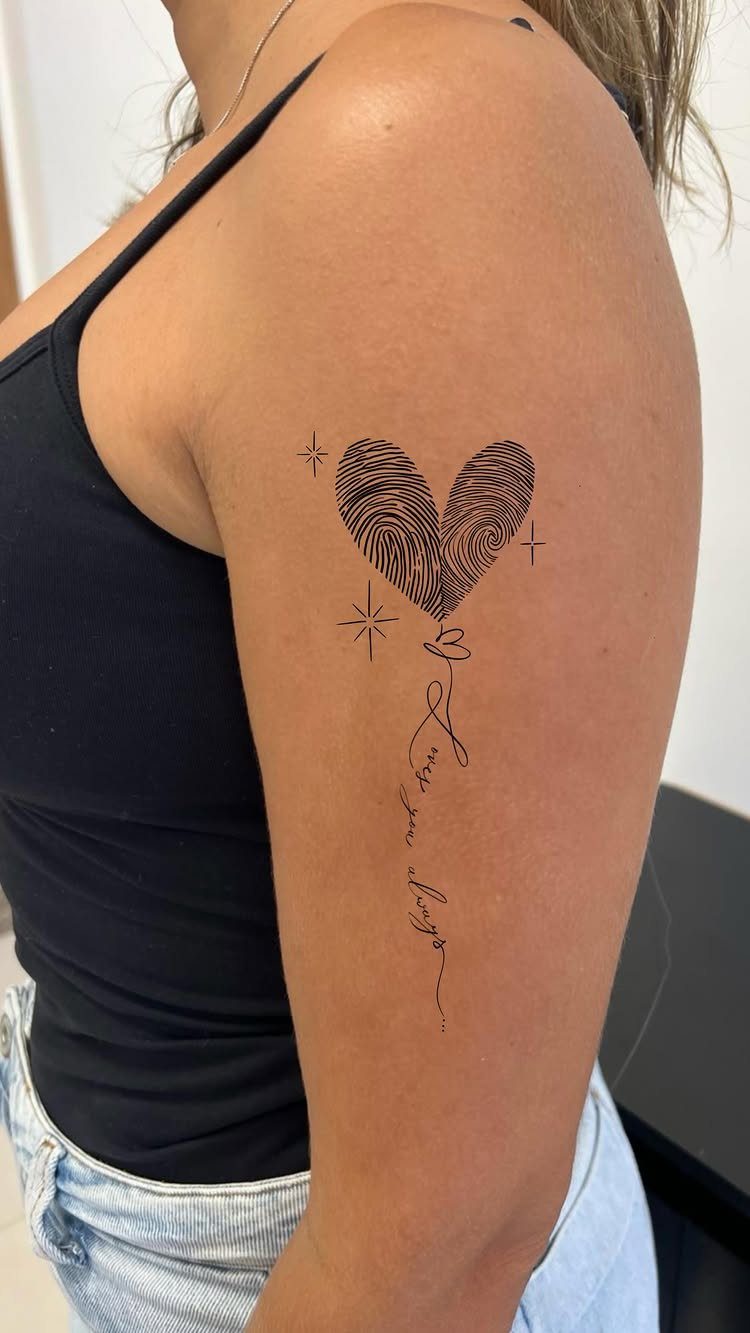 Fingerprint heart tattoo on an upper arm with stars and cursive script.