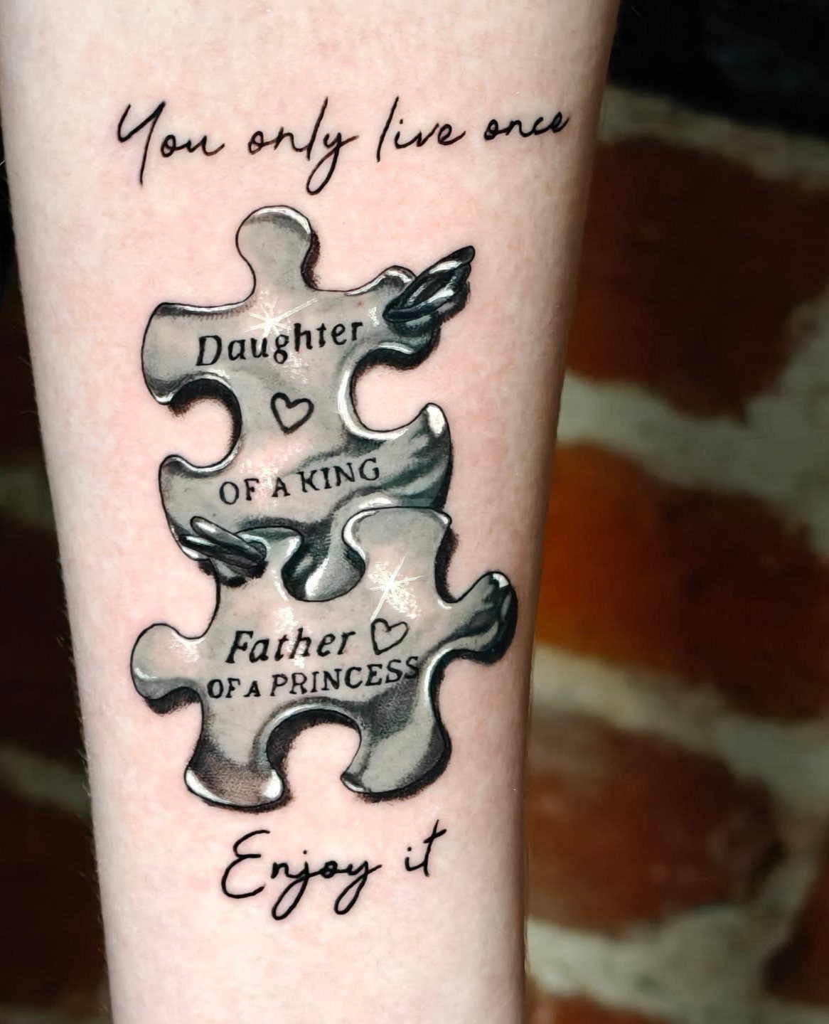 Two interlocking metallic puzzle piece tattoos with text about father and daughter.