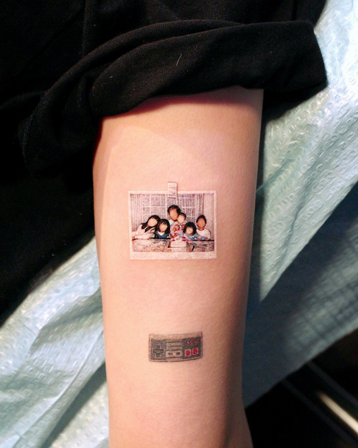 Family portrait tattoo and a cassette tape tattoo on a person's forearm