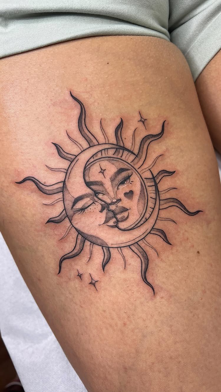 Sun and crescent moon tattoo with faces kissing on a person's thigh
