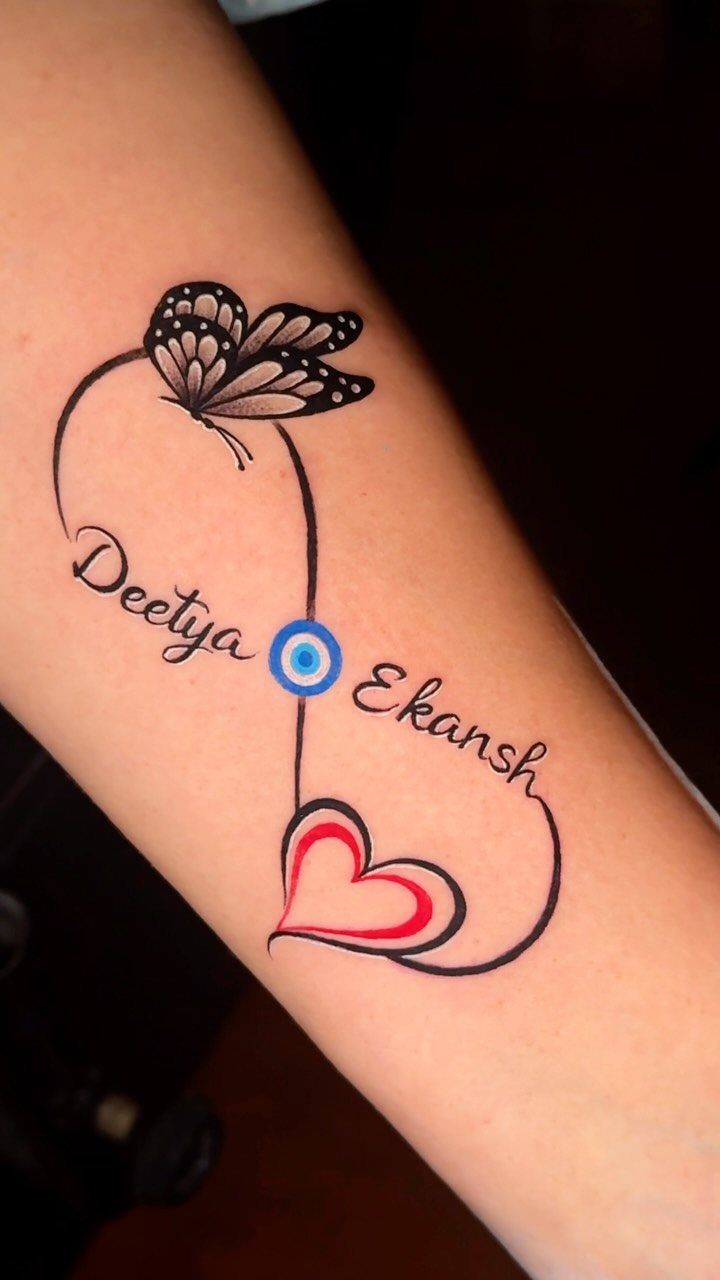 Tattoo on arm with names Deetya and Ekansh inside an infinity symbol and heart.