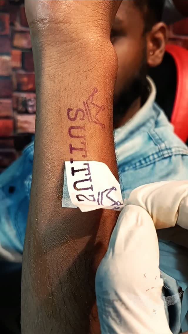 Tattoo of the name SUTU with a small crown on a forearm