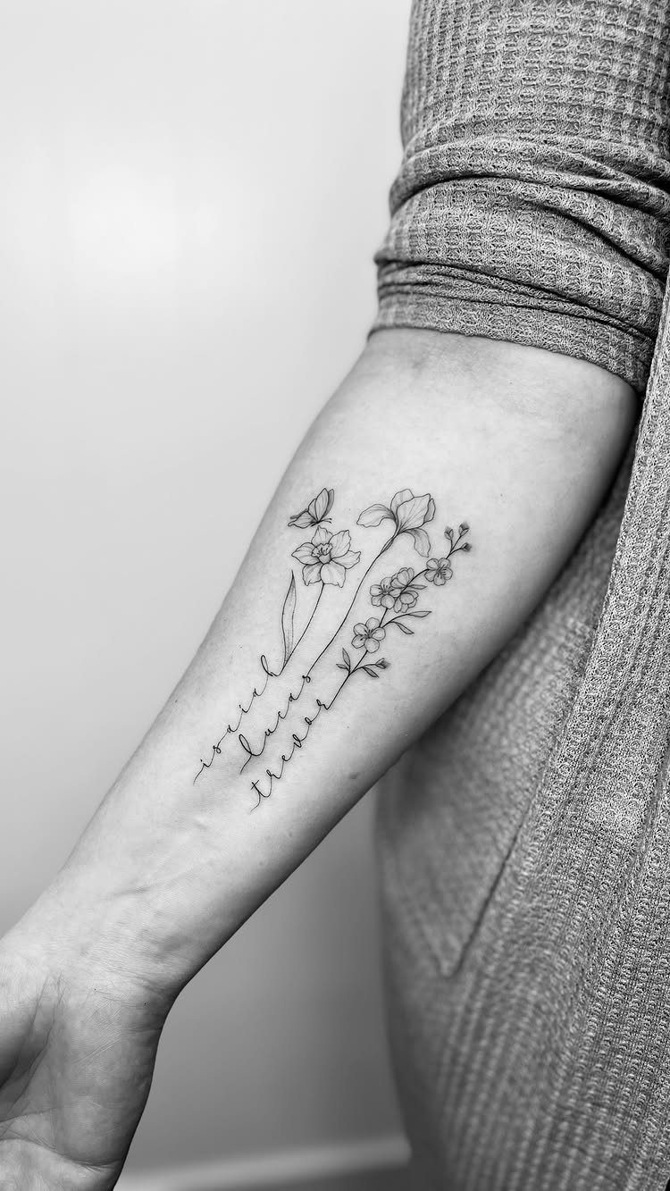 Forearm tattoo featuring cursive names entwined with delicate flowers and a small butterfly.