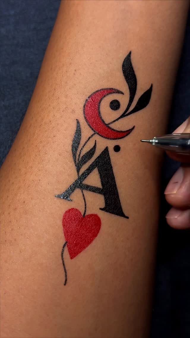 Tattoo of a black letter A with a red heart and crescent moon