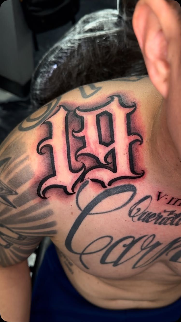 Old English letter G tattoo with red shading on a man's chest