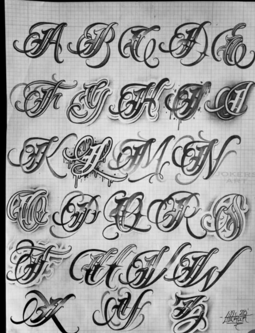 Ornate tattoo lettering alphabet drawn in black ink on lined white paper.