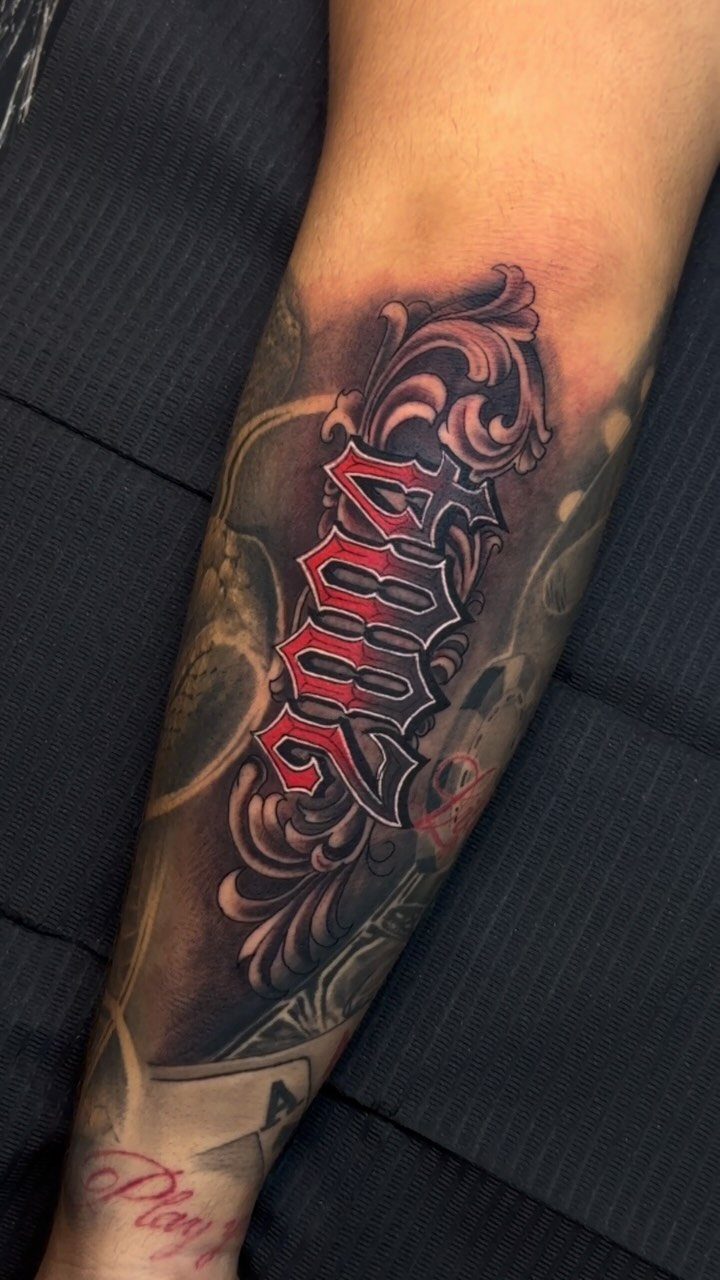 Old English tattoo of 2009 in red and black with ornate grey filigree