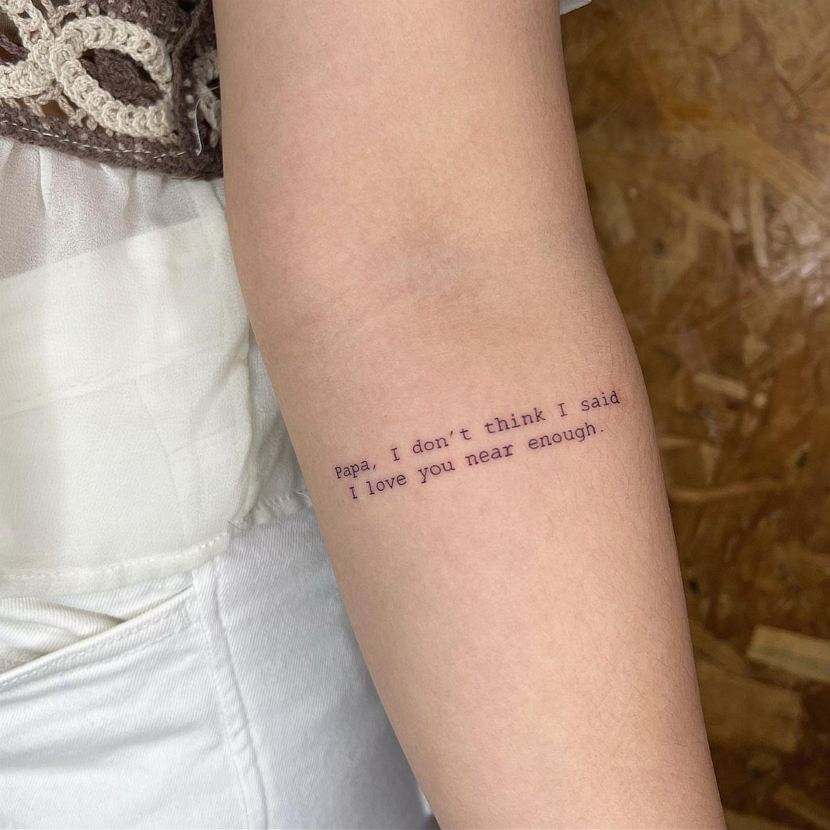 Typewriter font tattoo on a forearm with a sentimental quote about a father.