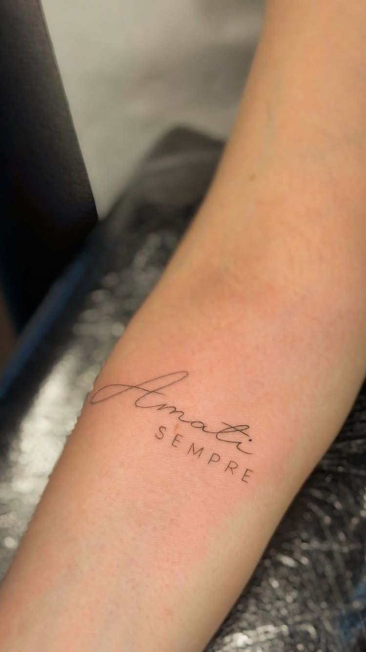 Fine line lettering tattoo on a forearm reading Amati SEMPRE in black ink.