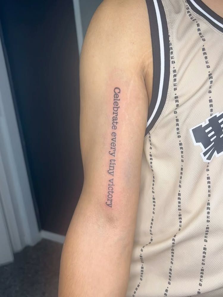 Typewriter font tattoo on an arm reading Celebrate every tiny victory