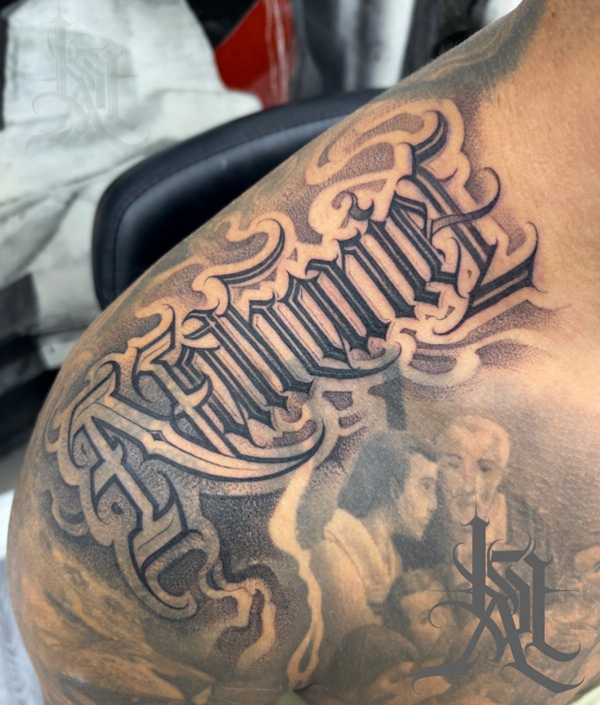 Gothic script name tattoo on a shoulder with a portrait and smoke.