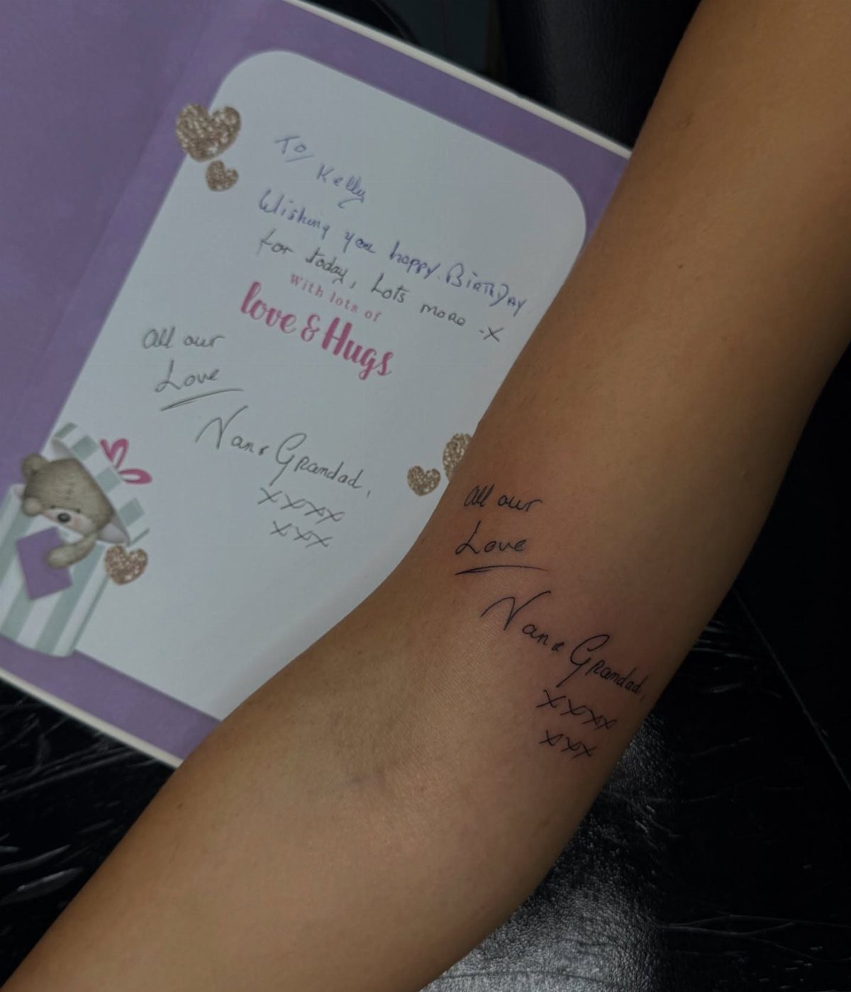 Forearm tattoo of handwritten names and love message next to original birthday card